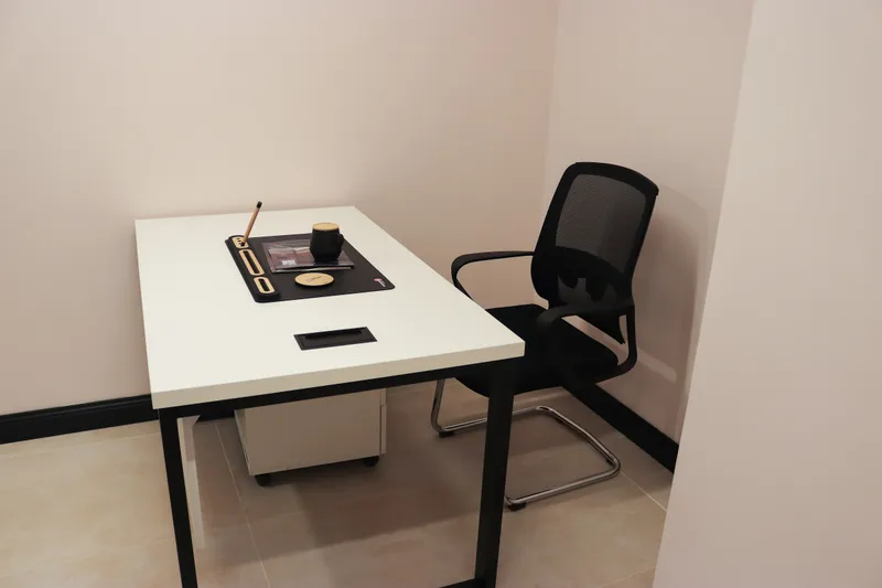 Office 27 · white desk with a desk mat and mug beside a mesh visitor chair